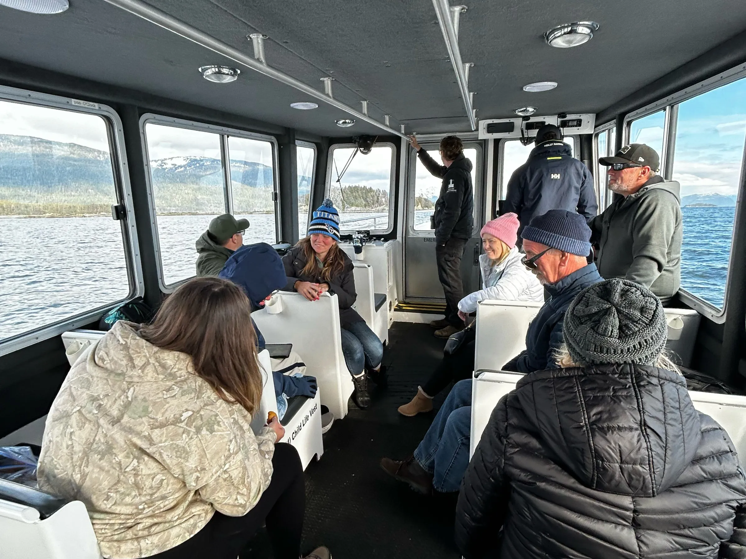 People sitting inside a boat cabin, wearing casual outdoor clothing.